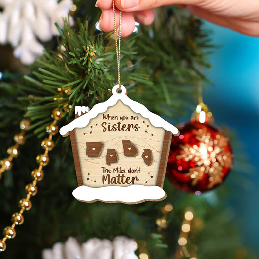 Personalized Christmas ornament with sisters quote and state shapes hanging on tree branch