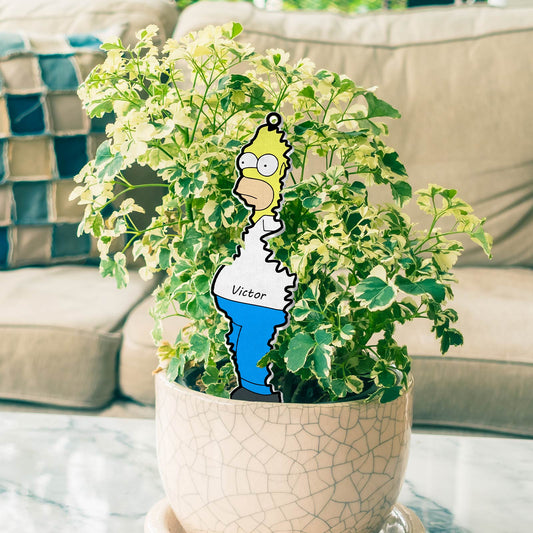 Personalized Christmas acrylic ornament featuring a cartoon character hanging on a potted indoor plant