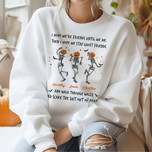 Woman wearing a white custom best friend Halloween sweatshirt showing three dancing skeletons with pumpkin heads and names