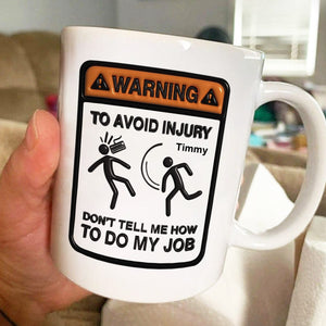 White coffee mug featuring a humorous warning sign stating 'Don't tell me how to do my job' as a unique workplace humor gift